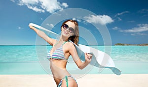 Woman in bikini and sunglasses with towel on beach