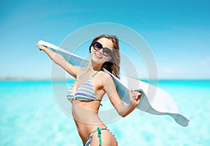 Woman in bikini and sunglasses with towel on beach