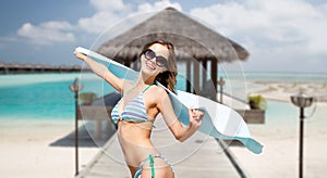 Woman in bikini and sunglasses with towel on beach