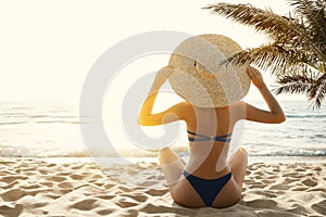 Woman Bikini Tropical Beach Back View. Beauty Model Girl in Sumer Hat Sun Tanning under Palm. Summer Beach Vacation. Holiday Sea