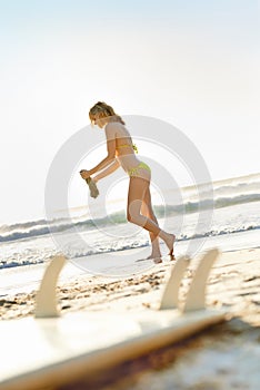 Woman, bikini and walking on beach sand for summer with surfing, holiday peace and watersports. Surfer girl, ocean and