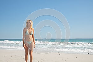 Woman in bikini walking on the beach in the sunshine