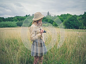 Woman with binoculars standing in meadow