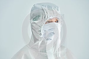 Woman in bio-hazard suit and face shield on white background.