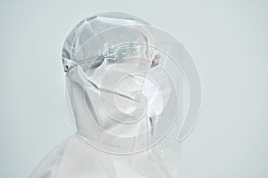 Woman in bio-hazard suit and face shield on white background.