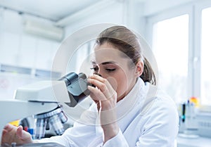 Woman biologist looking through microscope