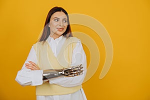 Woman with bionic prosthesis crosses arms by yellow wall