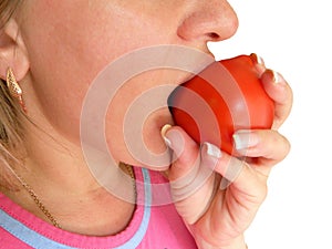 Woman bites and eats tomato closeup image. Part of face with mouth and lips. Red vegetable is in fingers with clear nails.