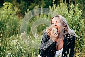 A woman bites a green Apple. Healthy diet