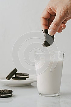 Woman with a bitten and soaked chocolate cookie in a glass of milk