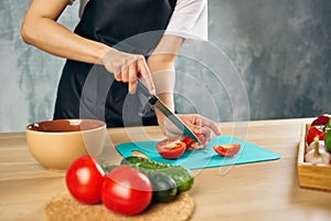 Woman in black apron on the kitchen cutting vegetables salad diet