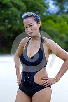 Woman black bikini show shape symbol on beach