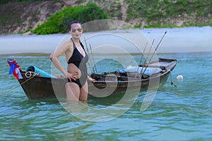 Woman black bikini with small boat on beach