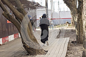 A woman in a black burqa walks down the street. A Muslim woman walks through the city