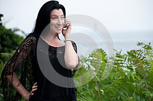 Woman in Black on Cellphone by the Sea