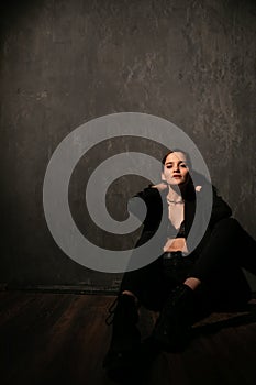 Woman in black clothes posing in a dark room