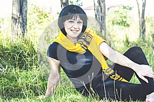 Woman in black clothes is sitting on the grass field