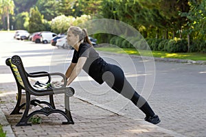 a woman in black clothes trains on a park bench . morning sports training for women& x27;s health sports lifestyle real life