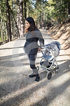 Woman in black clothing holding a stroller in the forest