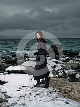 woman in a black coat outdoors landscape ocean dark clouds gothic