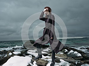 woman in a black coat outdoors landscape ocean dark clouds gothic