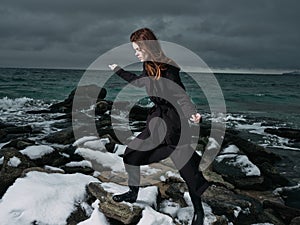 woman in a black coat outdoors landscape ocean dark clouds gothic