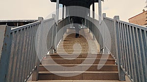 Woman with black coat walking up the stairs of the footbridge
