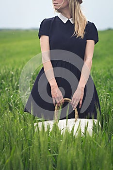 Woman with black dress in a field of green wheat