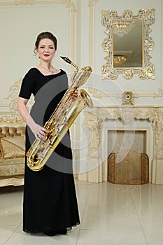 Woman in black dress hold baritone saxophone in photo