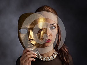 Woman in a black dress with a pearl necklace and old mask