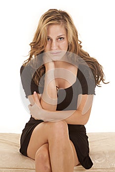 Woman black dress sit facing serious cross legs