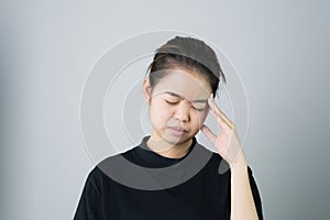 Woman in a black dress is touching head to show her headache. Causes may be caused by stress or migraine.