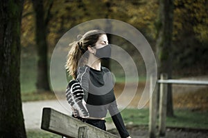 Woman with black face mask exercising in park during covid-19 epidemy