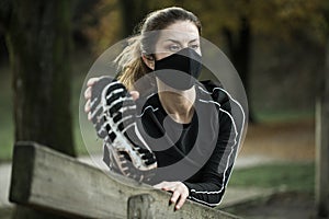 Woman with black face mask exercising in park during covid-19 epidemy