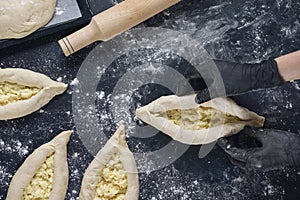 Woman in black gloves holds raw khachapuri. Process of making bakery. Adjarian Khachapuri Recipe Ã¢â¬â Georgian cheese bread. Top