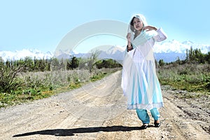 Woman with black hair in blue sari, on the rular road, nature