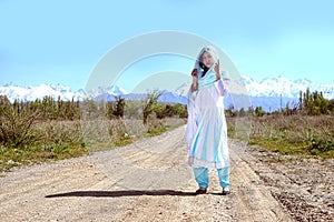 Woman with black hair in blue sari, on the rular road, nature