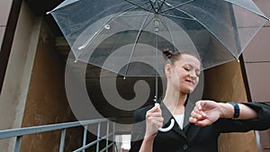 A woman in a black jacket under a transparent umbrella, on the street of the city, outdoors. Rain.