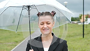 A woman in a black jacket under a transparent umbrella, on the street of the city, outdoors. Rain.