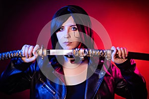 woman in a black leather jacket with a katana in her hands posing  on a dark background with red backlights