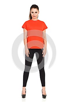 Woman In Black Leggings And Oragne Shirt Is Standing Legs Apart