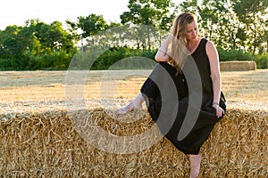 Woman in black long dress looking in camera standing in the field