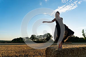 Woman in black long dress looking in camera standing in the field