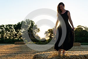 Woman in black long dress looking in camera standing in the field