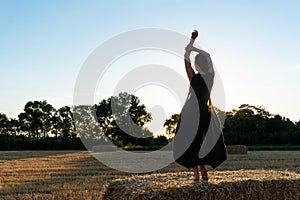 Woman in black long dress looking in camera standing in the field