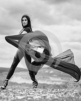 Woman in black overalls dancing with flying fabric