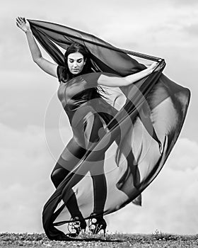 Woman in black overalls dancing with flying fabric