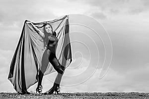 Woman in black overalls dancing with flying fabric