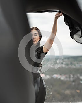 Woman in black overalls dancing with flying fabric