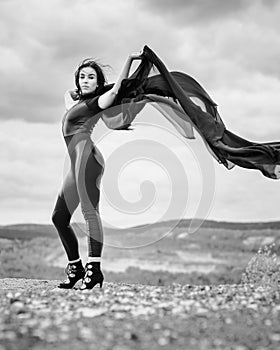 Woman in black overalls dancing with flying fabric